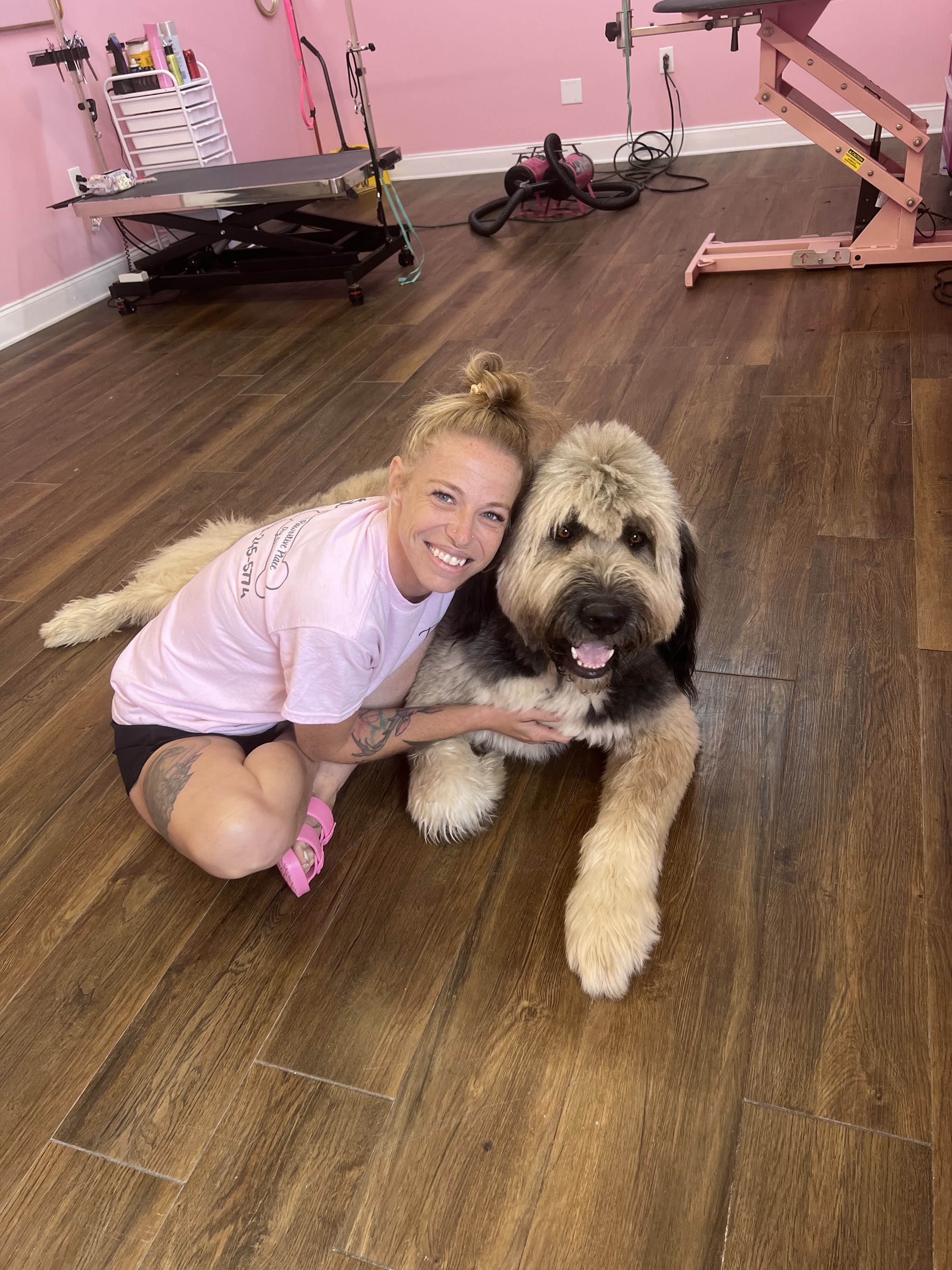 One of our groomers sitting on the floor with a happy doodle